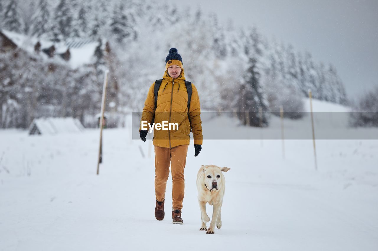 Man and dog walking on snow
