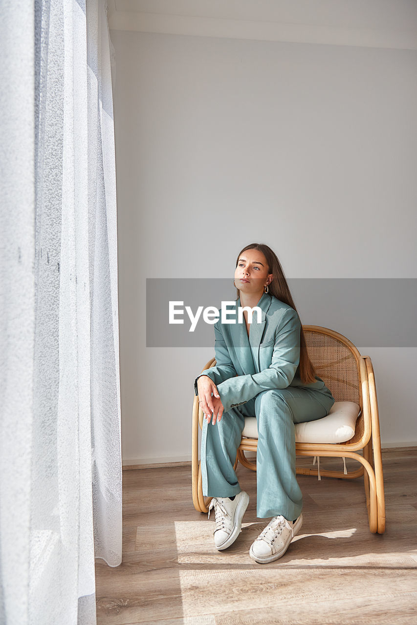 Young woman sitting on chair at home