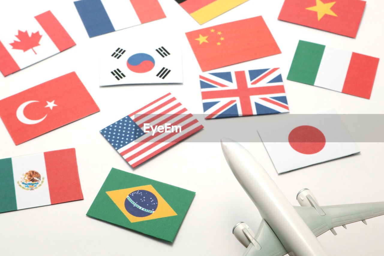 Close-up of various flags by toy airplane against white background