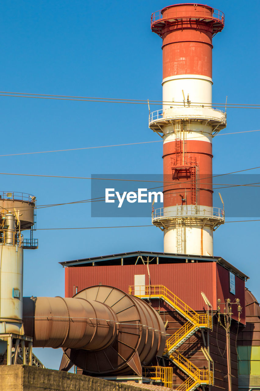 LOW ANGLE VIEW OF INDUSTRY AGAINST CLEAR BLUE SKY