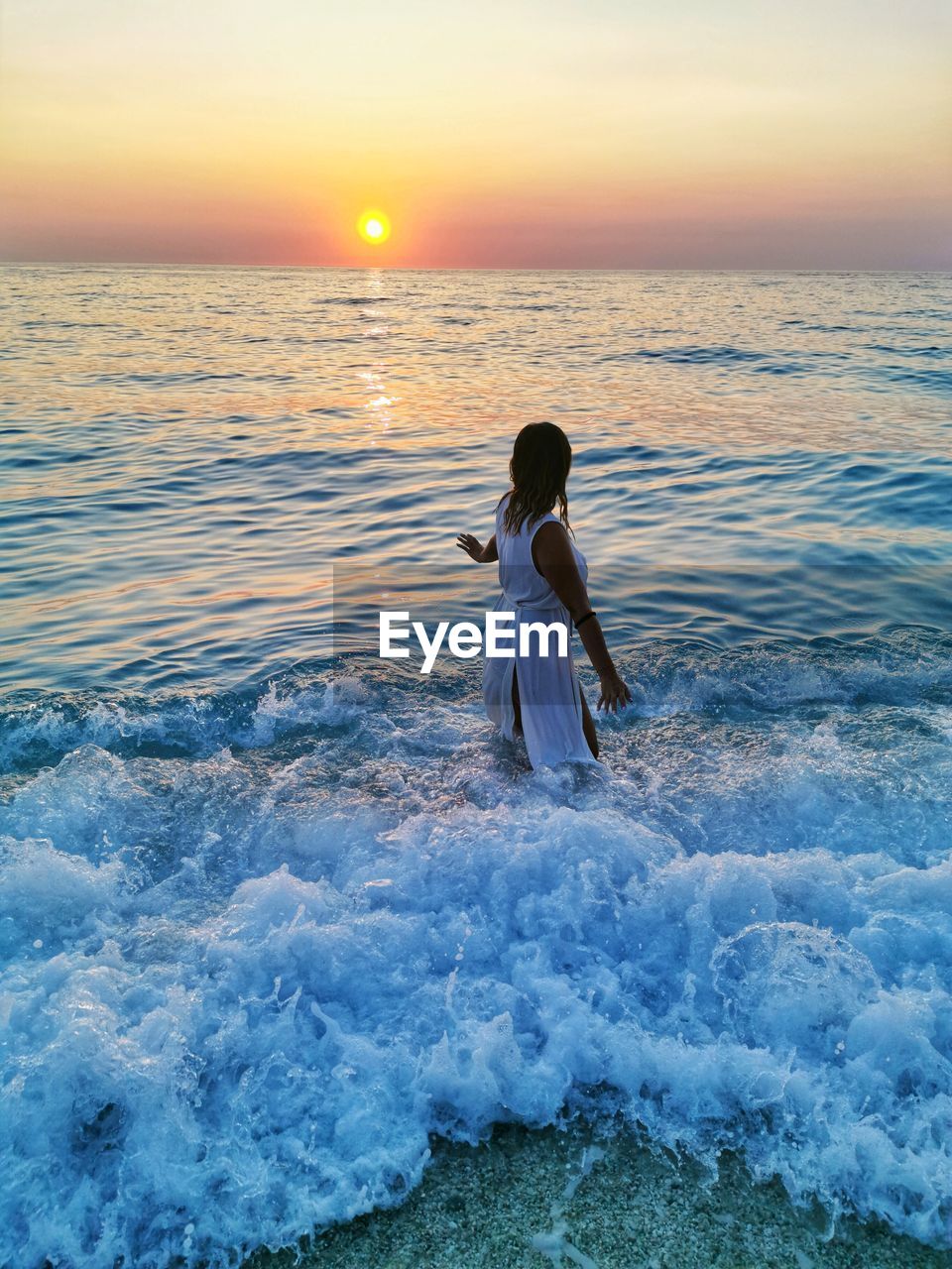 Woman on beach against sky during sunset