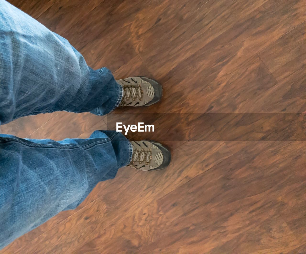 LOW SECTION OF MAN WEARING SHOES ON FLOOR