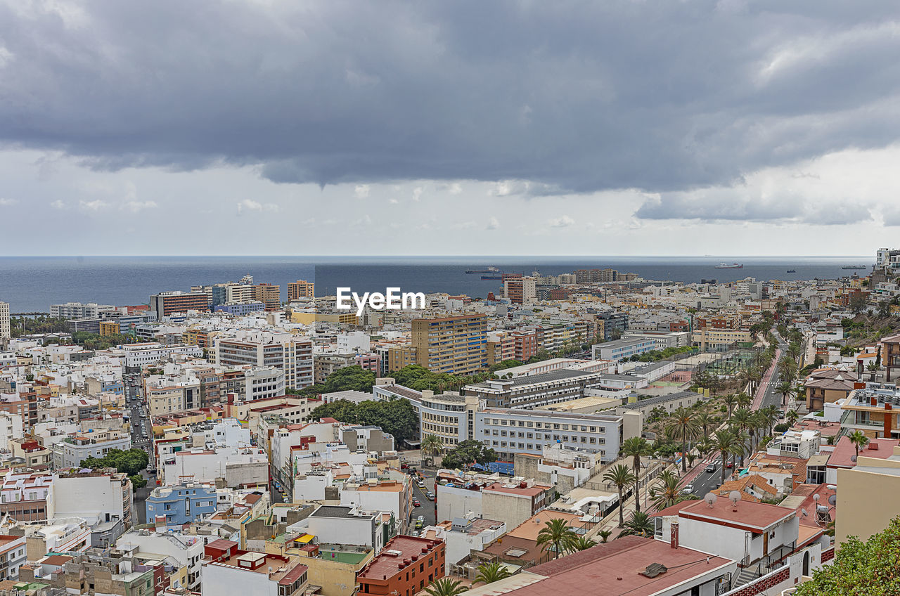 HIGH ANGLE SHOT OF TOWNSCAPE AGAINST SEA