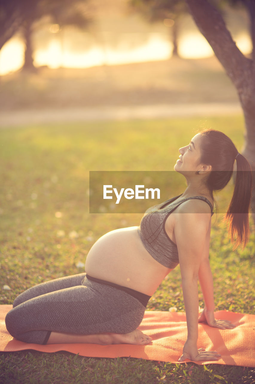 Pregnant woman doing yoga on field