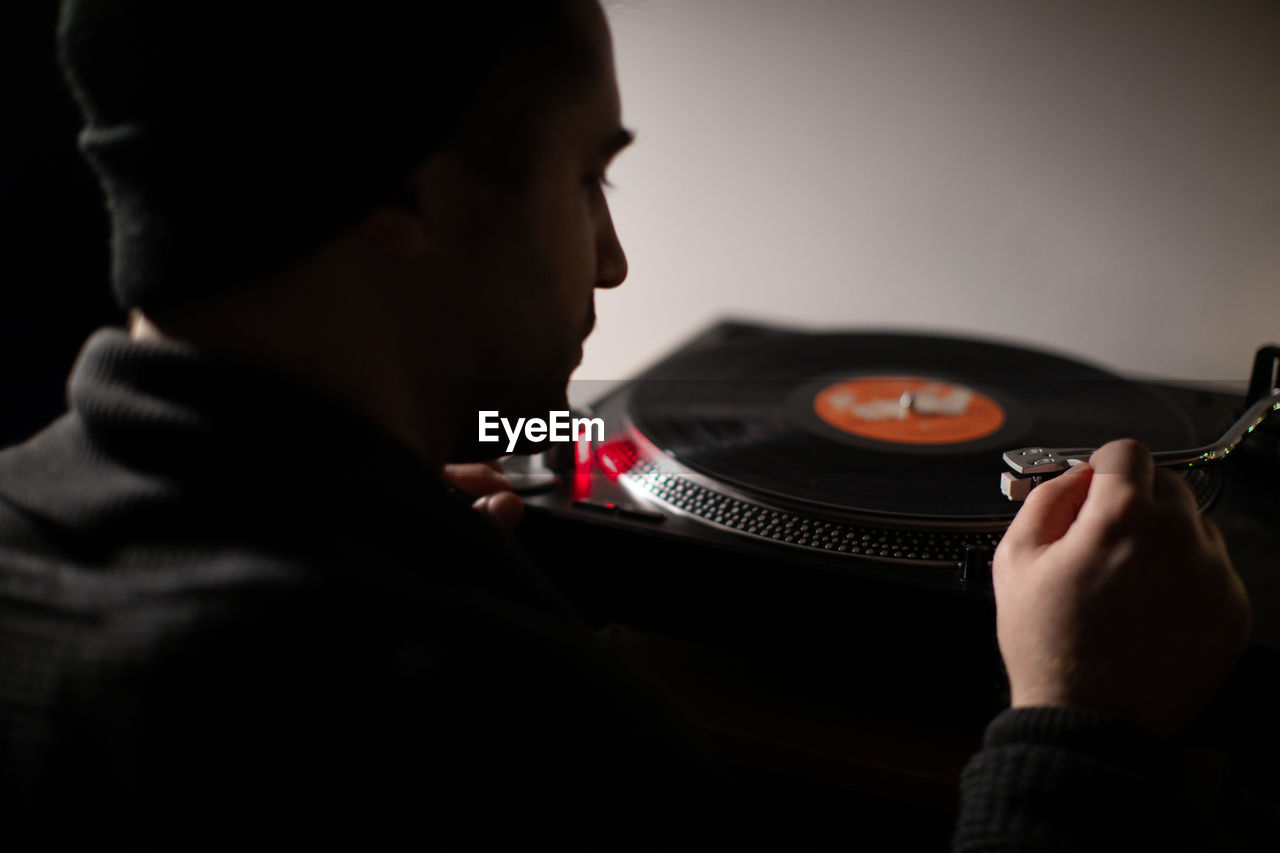 Rear view of man playing turntable