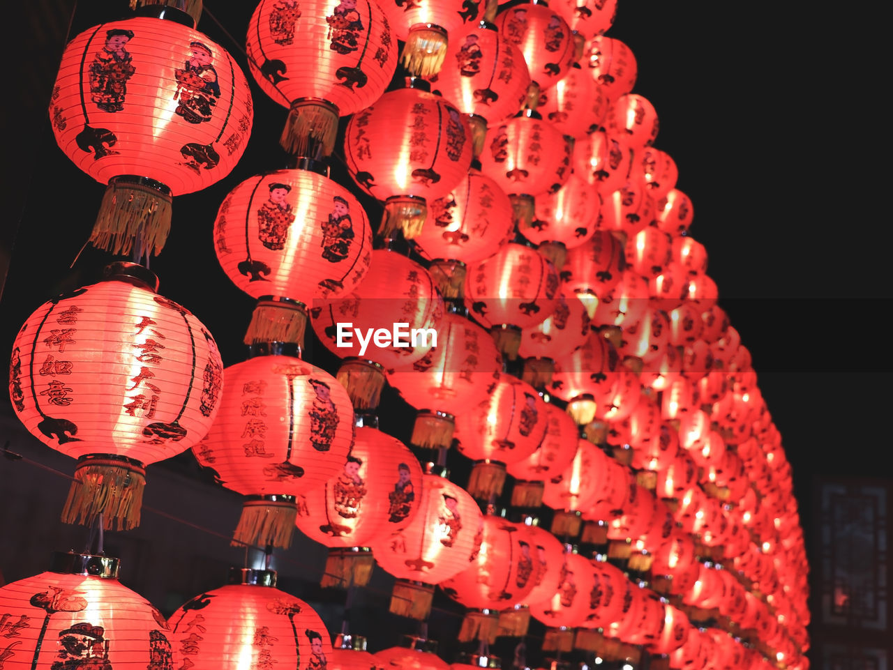 LOW ANGLE VIEW OF ILLUMINATED LANTERNS HANGING IN ROW