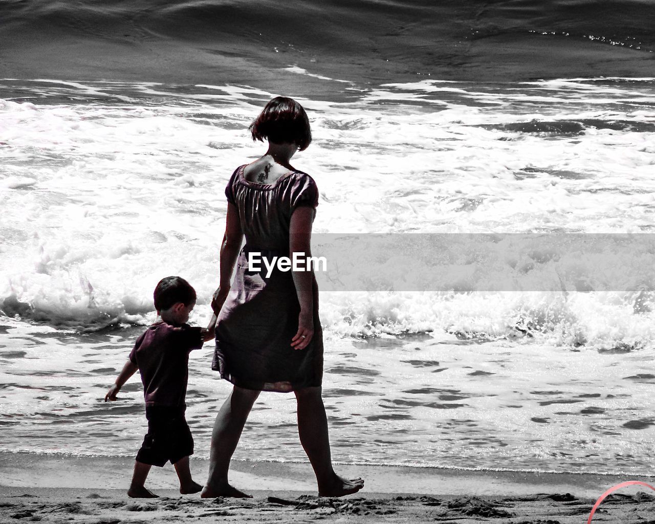 REAR VIEW OF FATHER AND DAUGHTER STANDING AT BEACH