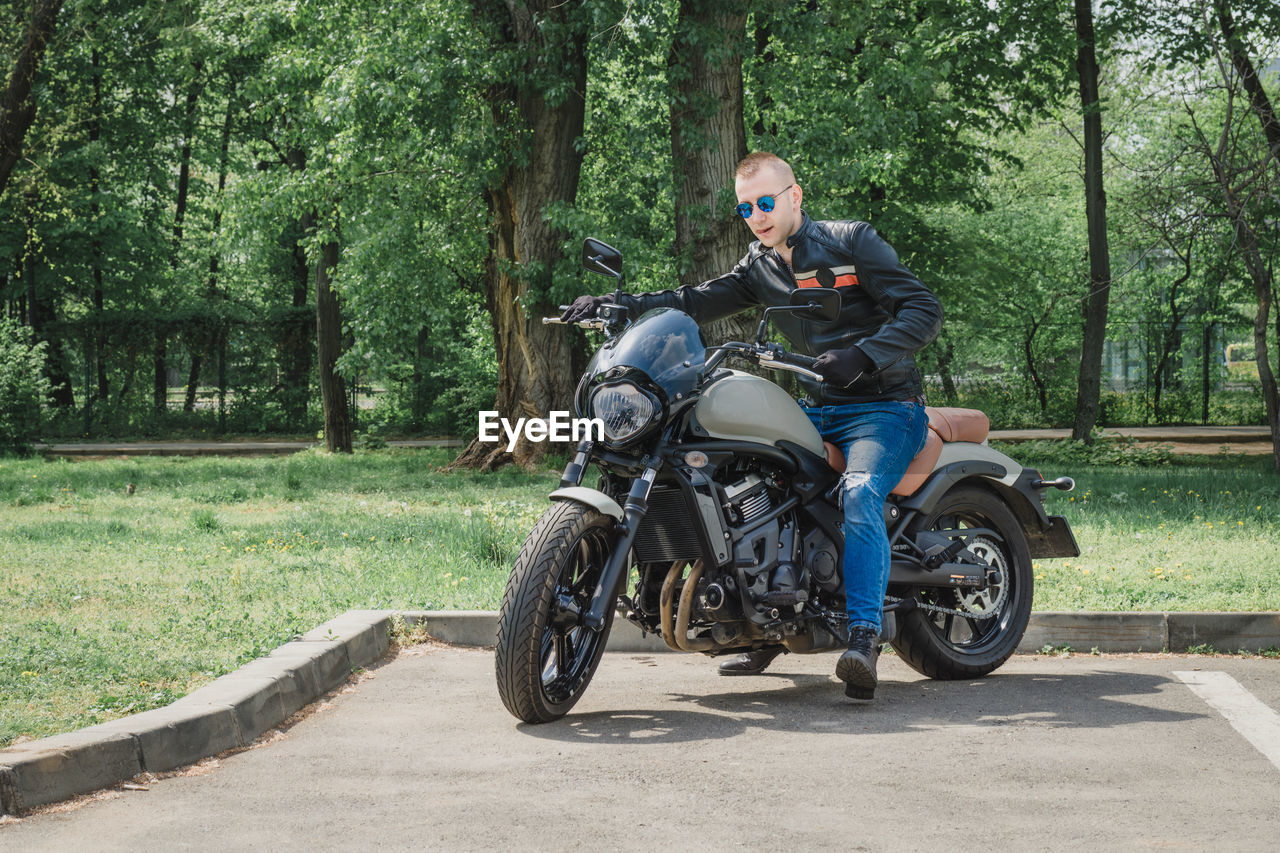 Man riding motorcycle on road against trees