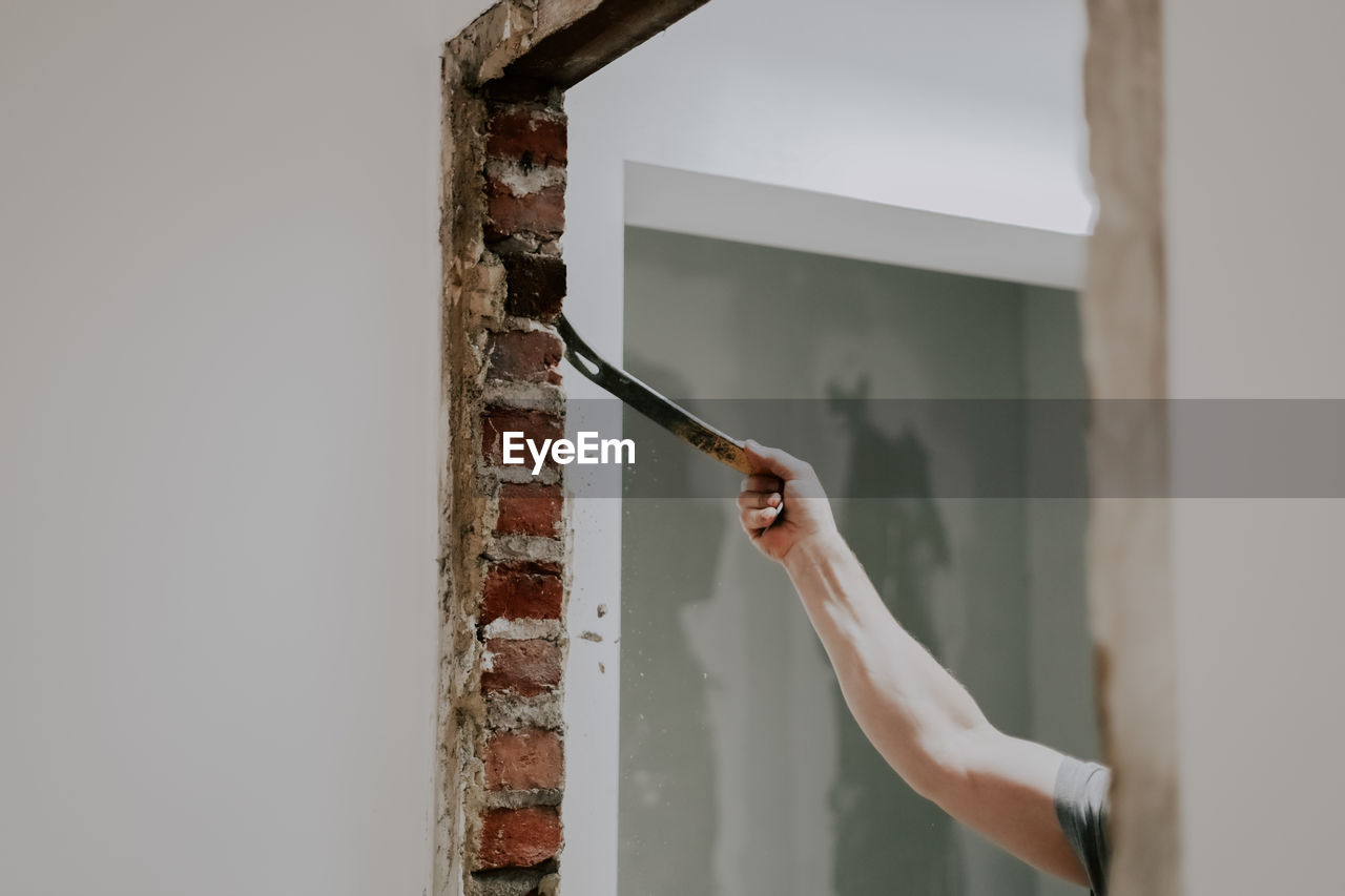 A man working with a crowbar in a doorway.