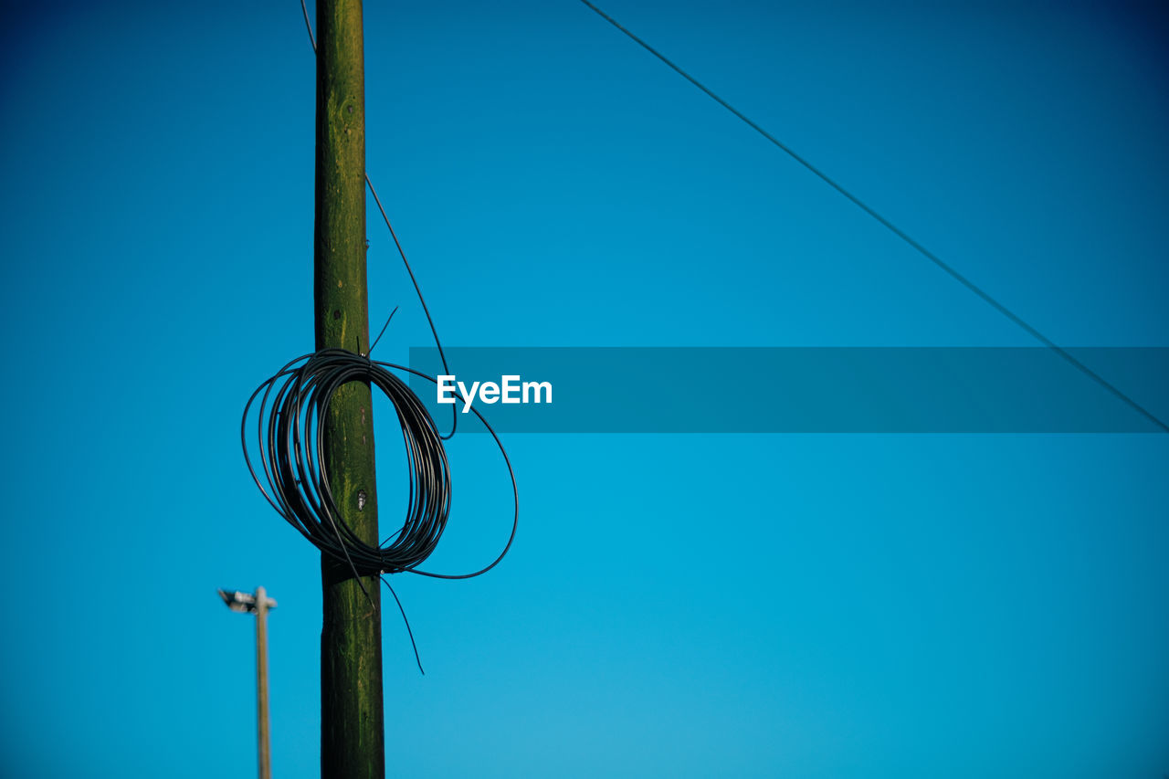 Low angle view of cables against clear blue sky