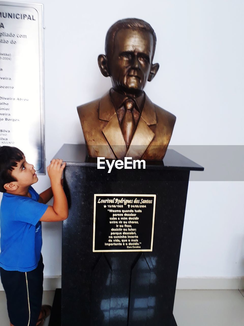 PORTRAIT OF BOY STANDING BY TEXT ON SHELF