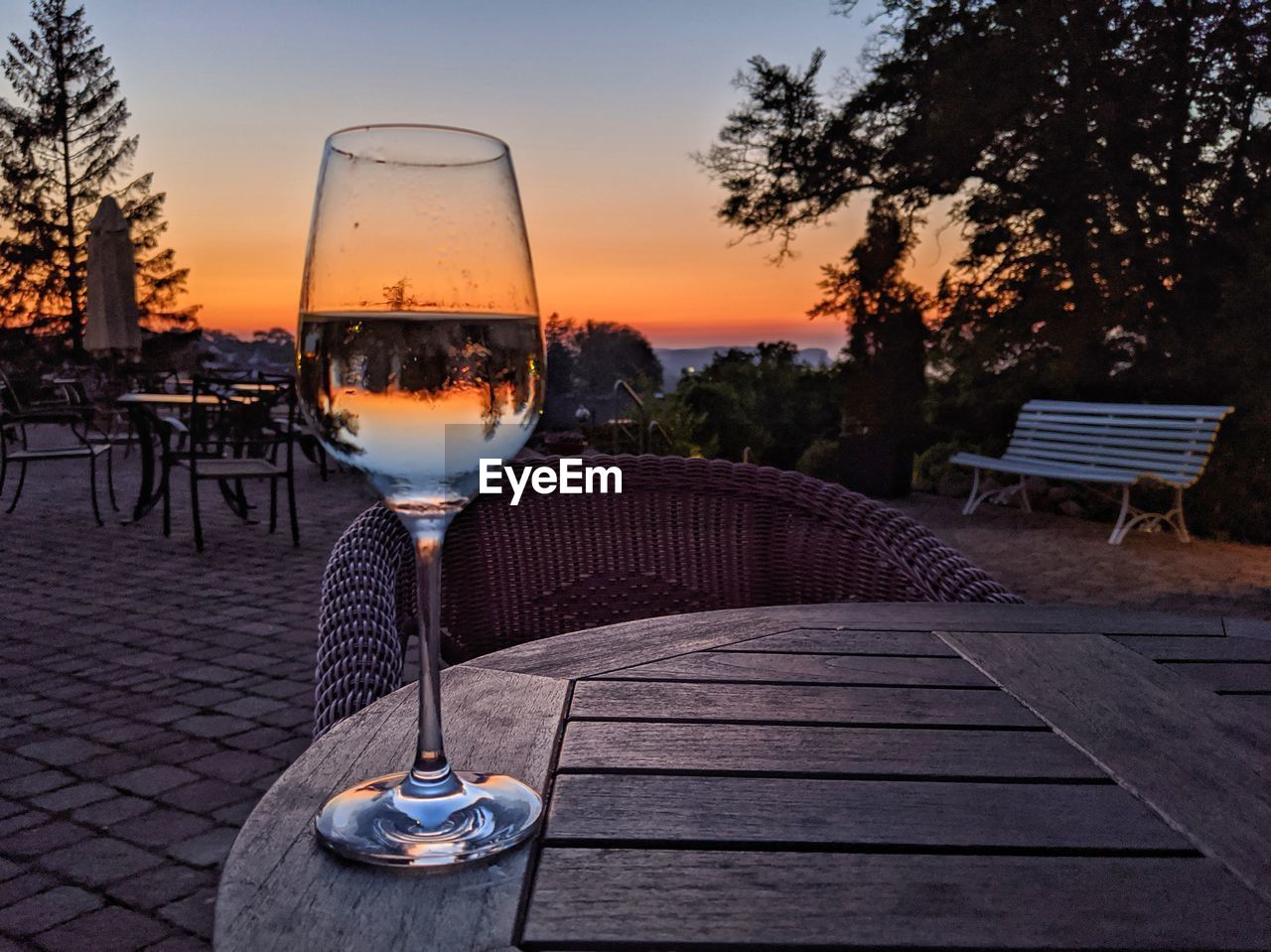 GLASS OF WINE ON TABLE AT SUNSET