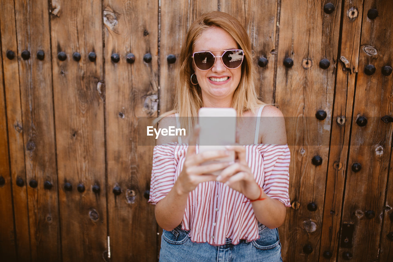 Blonde woman smiling and laughing as she looks at her cell phone