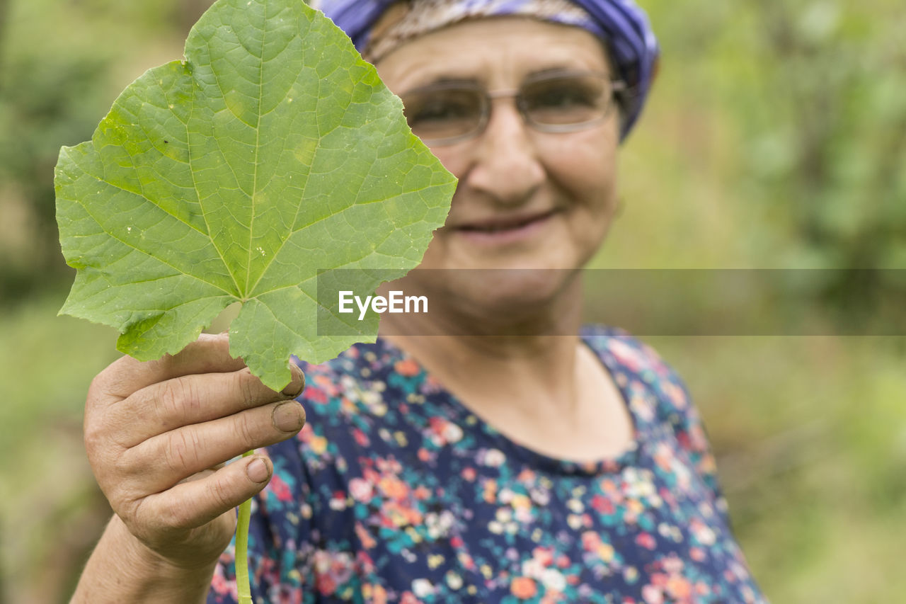 Close-up portrait of woman holding leaf