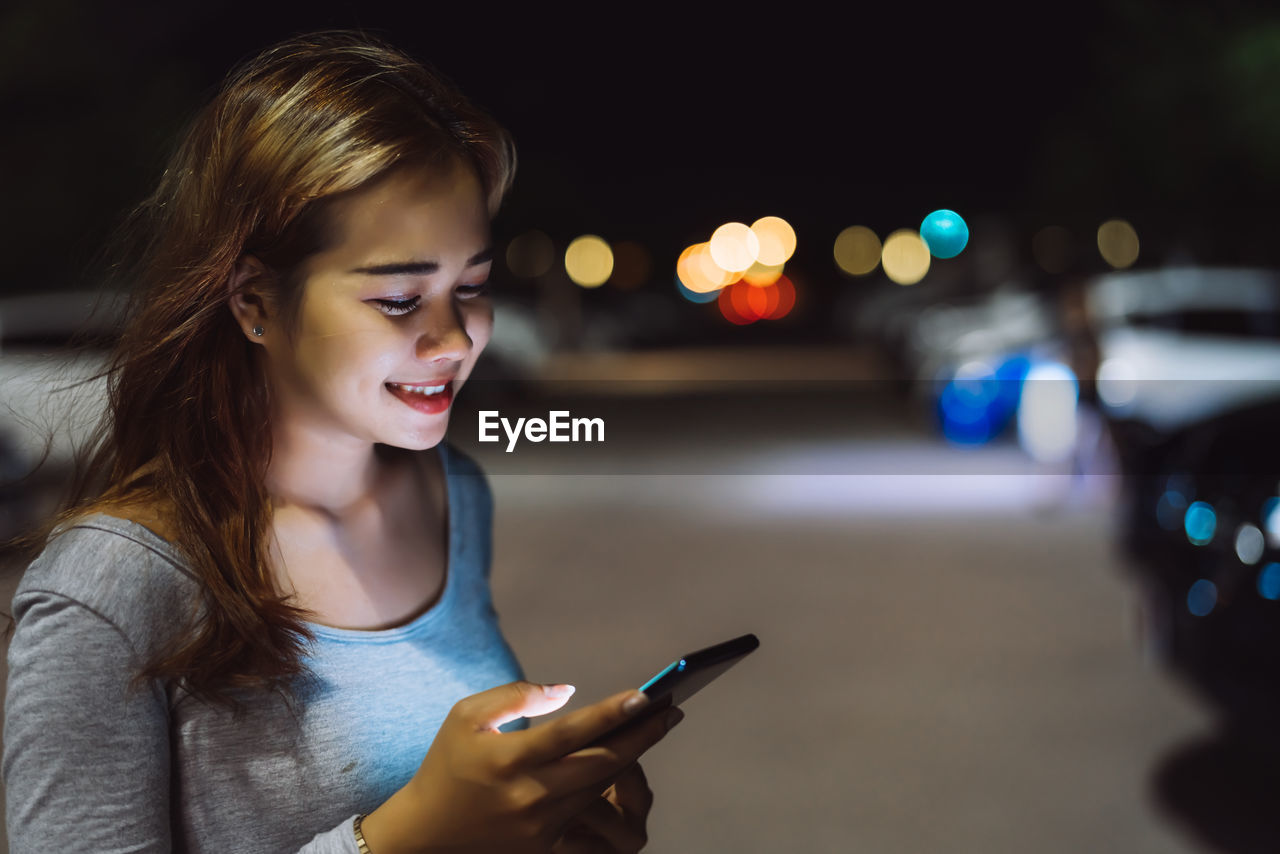 CLOSE-UP OF YOUNG WOMAN USING MOBILE PHONE