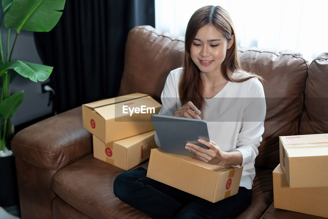 portrait of smiling young woman using digital tablet while sitting on table