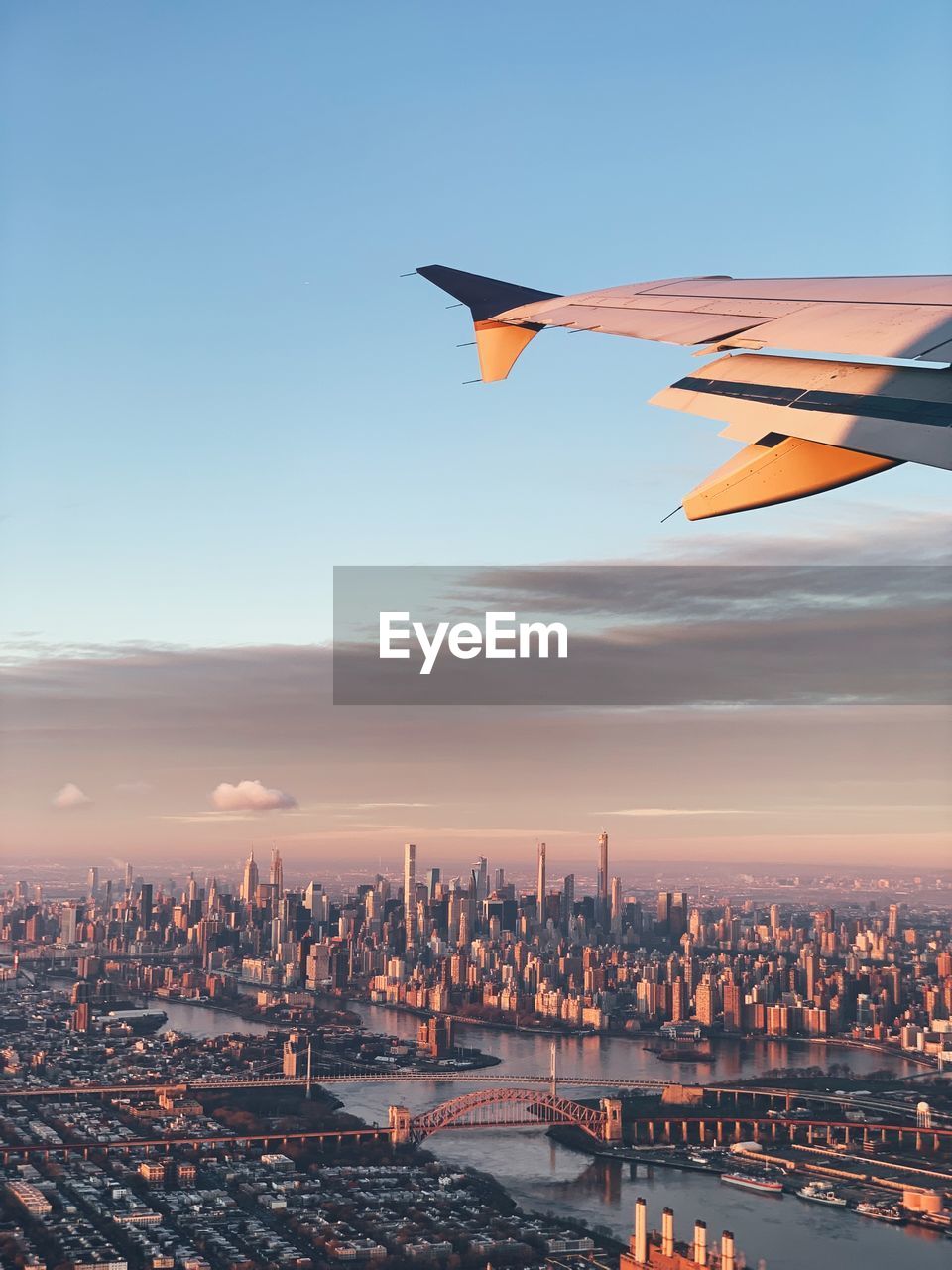 Cropped image of airplane flying over cityscape against sky