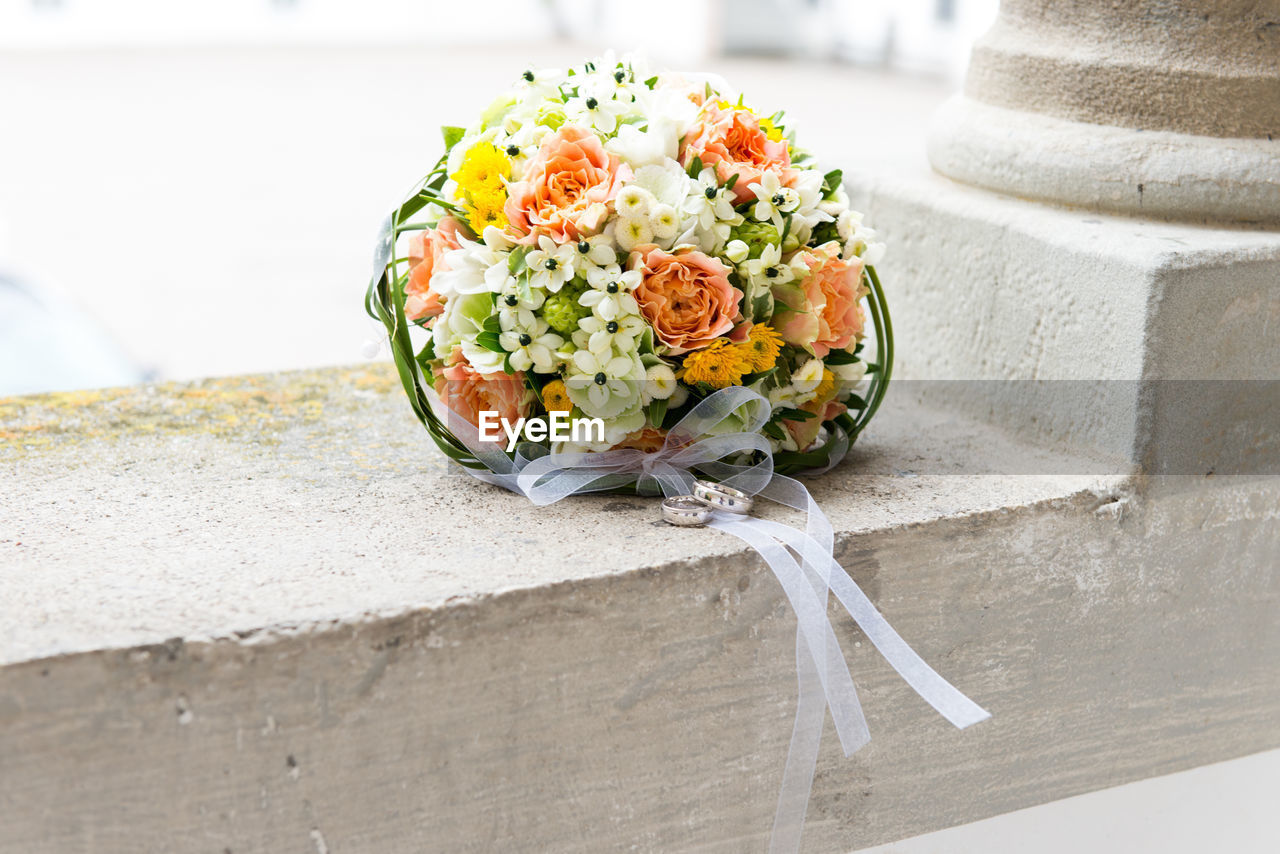 CLOSE-UP OF FLOWER BOUQUET ON TABLE AGAINST WALL
