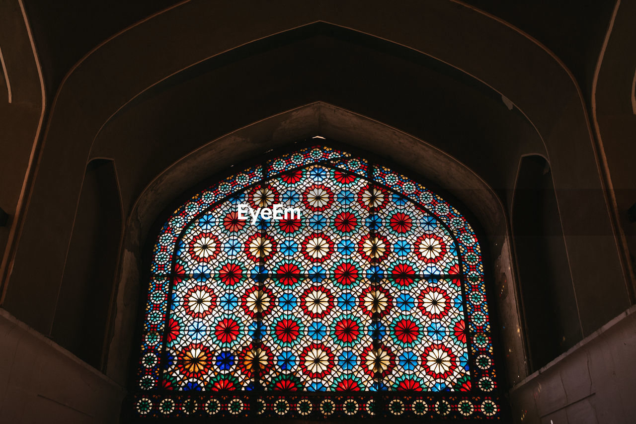 LOW ANGLE VIEW OF MULTI COLORED GLASS CEILING IN BUILDING