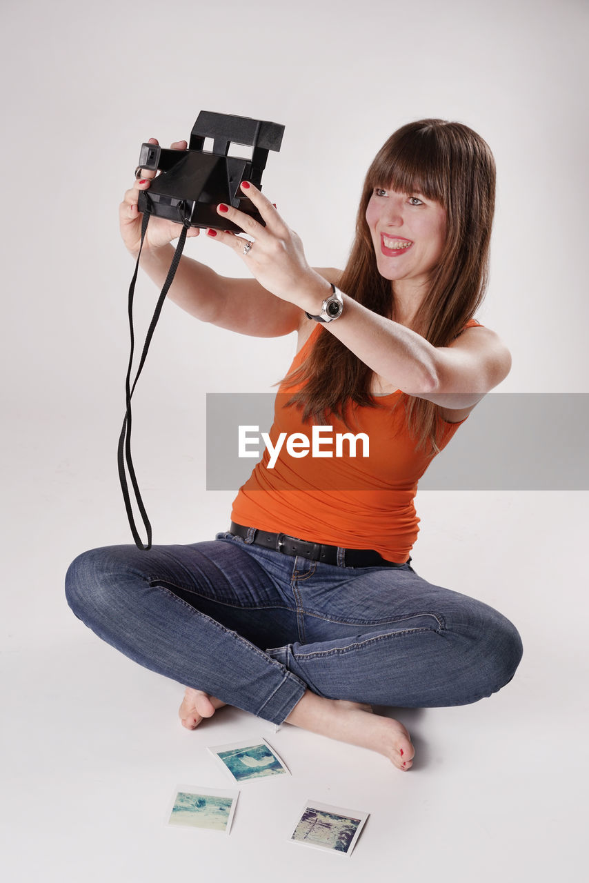 Beautiful woman taking selfie through camera against white background