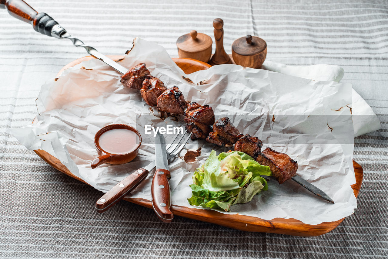 Barbecue with tomatoes and herbs on a wooden plate with paper