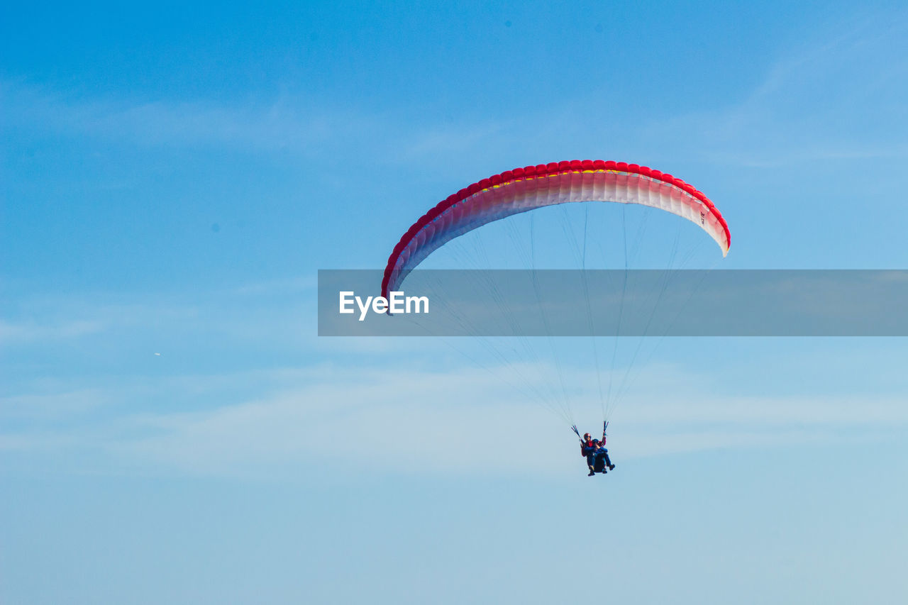Low angle view of person paragliding against blue sky during sunny day