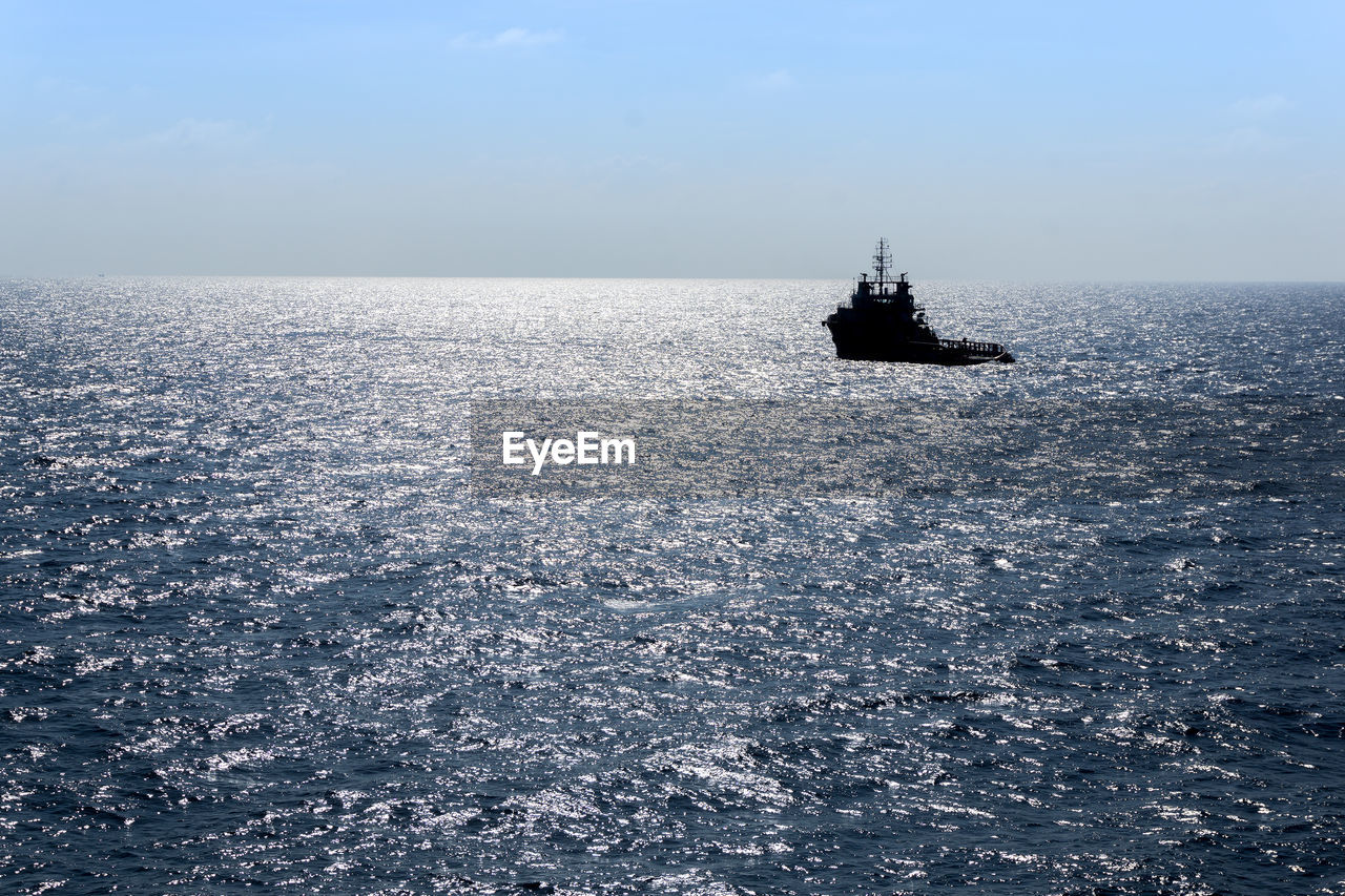 A silhouette of an anchor handling tug boat maneuvering at offshore terengganu oil field