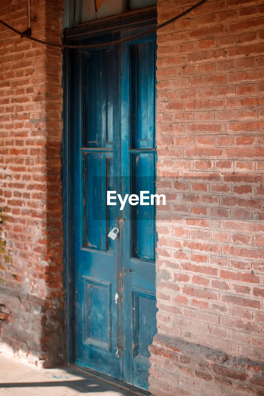 blue, architecture, door, entrance, building exterior, built structure, closed, brick, wall, building, wood, brick wall, house, old, no people, wall - building feature, protection, security, residential district, window, day, facade, city, front door, outdoors, weathered, doorway, door handle, history, iron