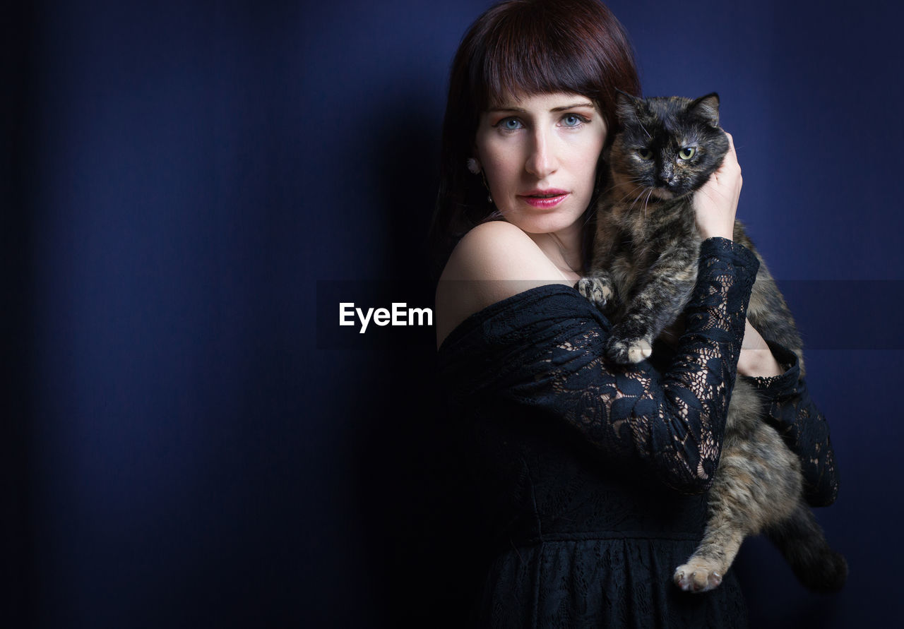 Studio portrait of caucasian woman with her cute cat isolated on blue background