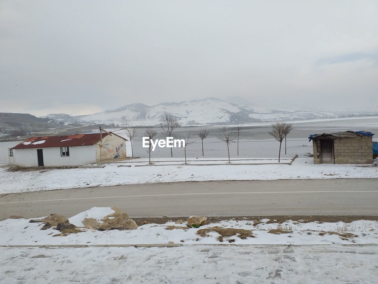 Snow covered houses by buildings against sky