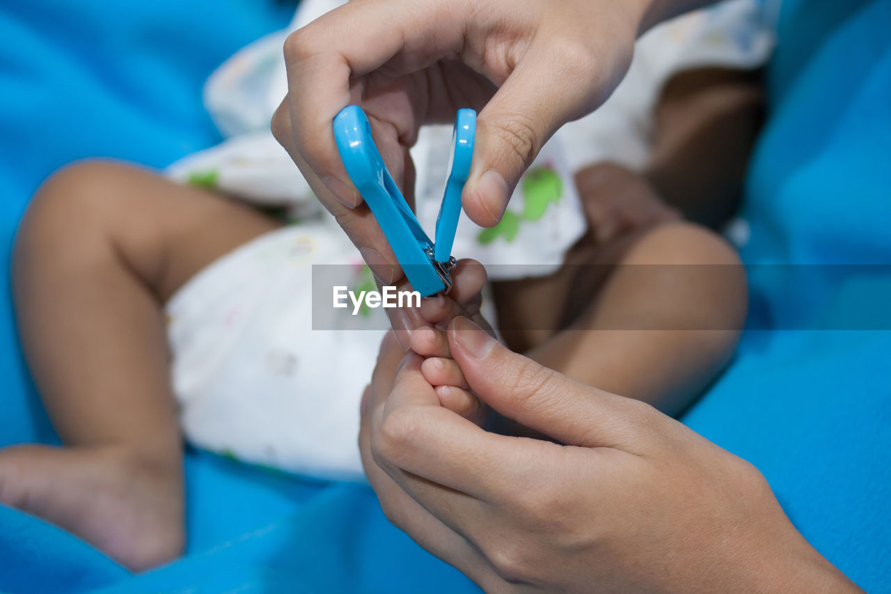 Close-up of mother cutting nails of baby at home