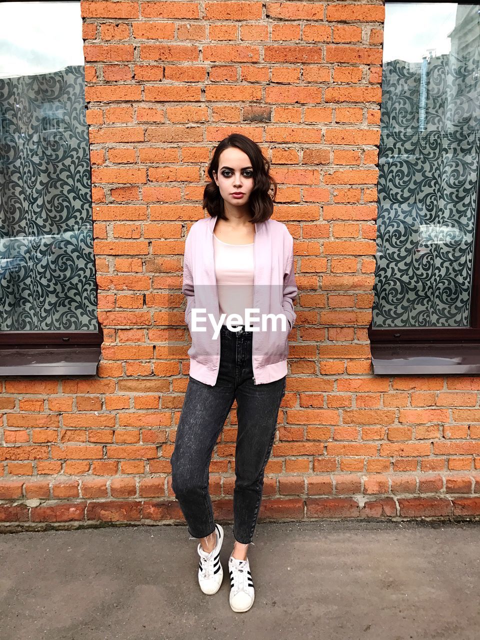 PORTRAIT OF YOUNG WOMAN STANDING ON BRICK WALL