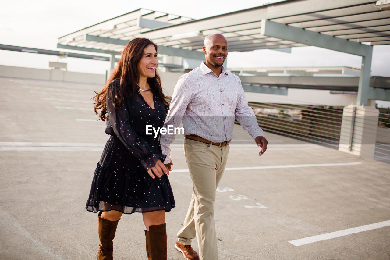 Multiracial late forties couple walking on rooftop in san diego