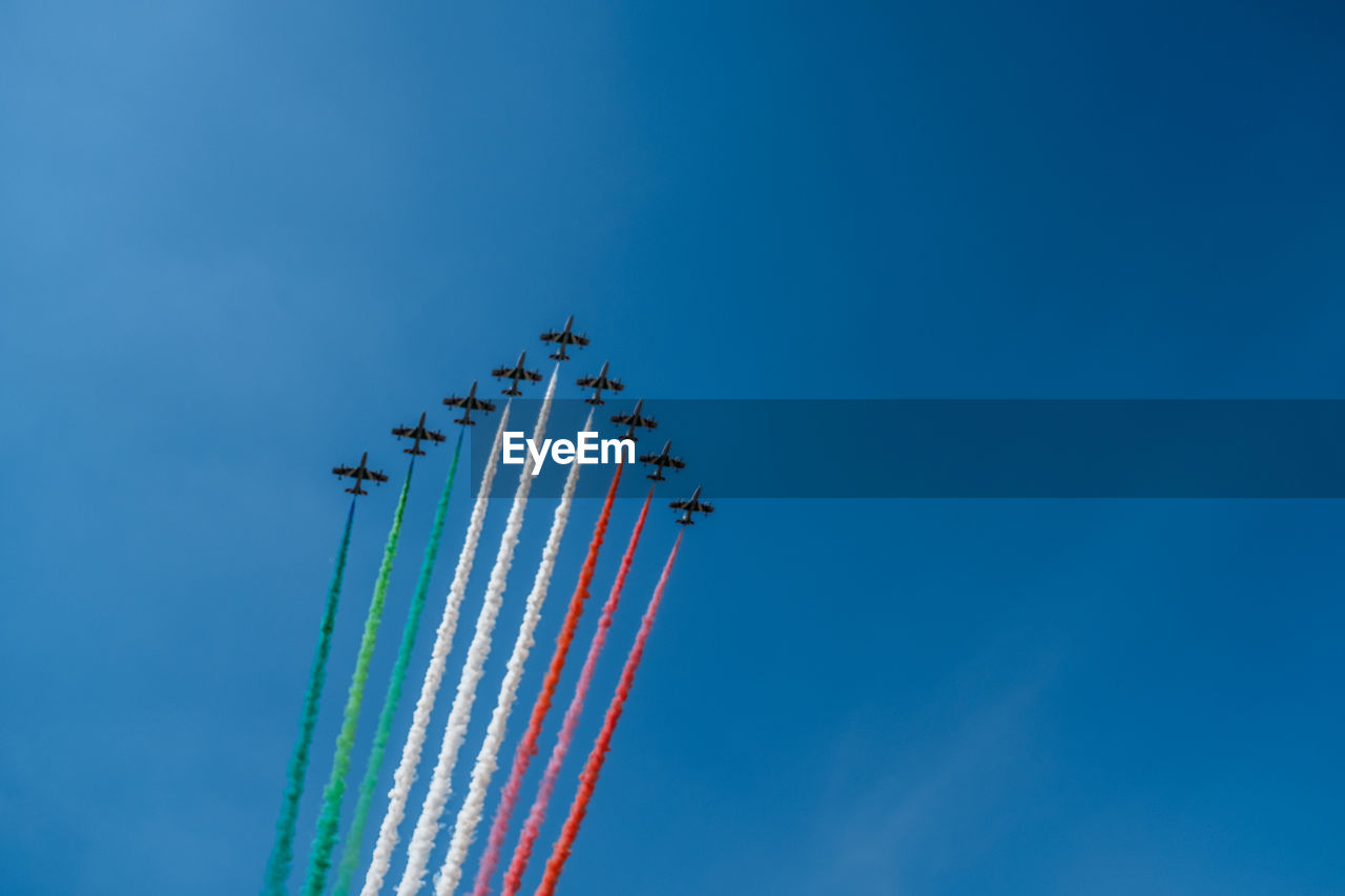 Low angle view of airplanes flying against blue sky