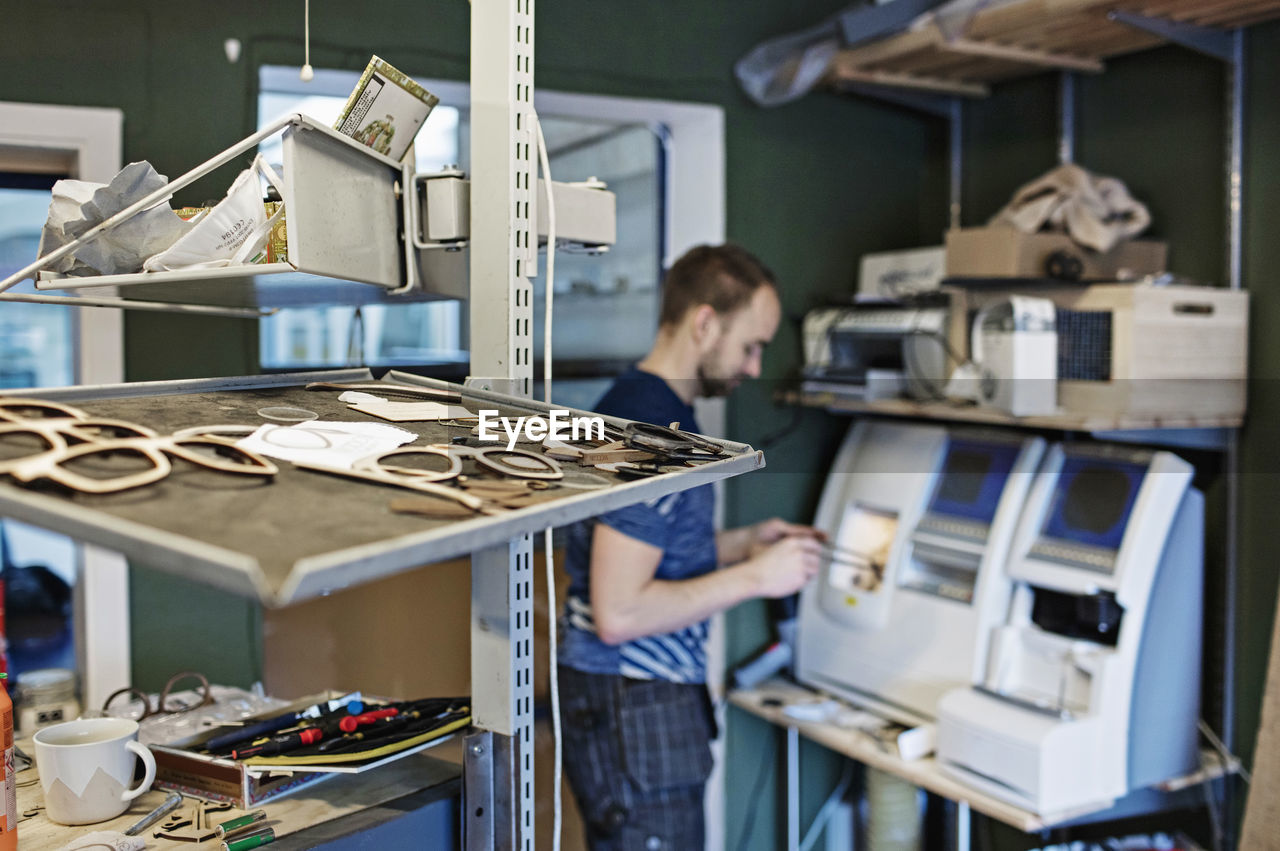 Male owner standing by machinery in workshop