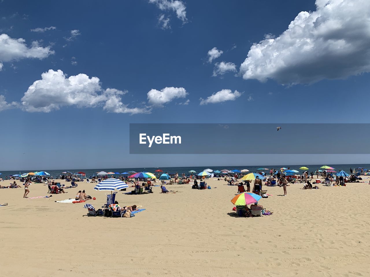 GROUP OF PEOPLE ON BEACH AGAINST SKY