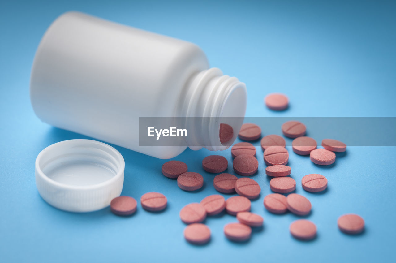 Close-up of medicines and bottle on blue background