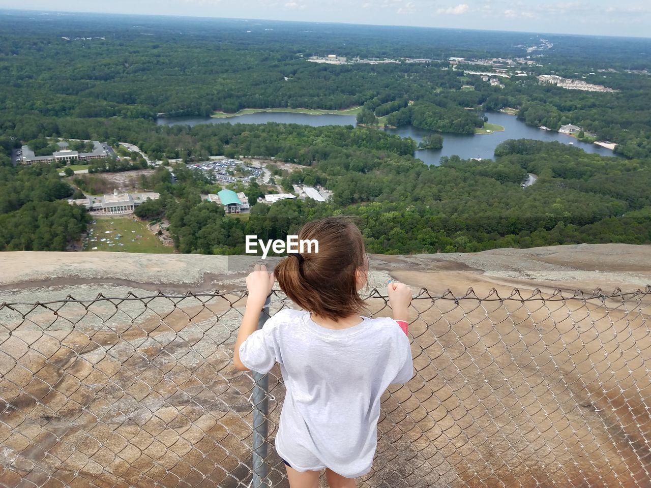 REAR VIEW OF WOMAN STANDING ON MOUNTAIN BY SEA