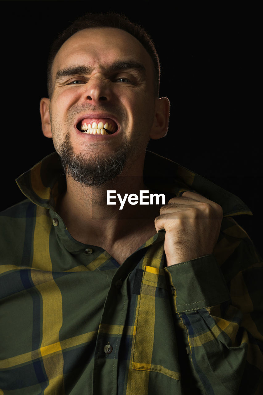 one person, portrait, adult, studio shot, black background, men, facial hair, headshot, emotion, beard, singing, front view, indoors, mouth open, person, looking at camera, young adult, human mouth, clothing, smiling, facial expression, hairstyle, happiness, anger, looking