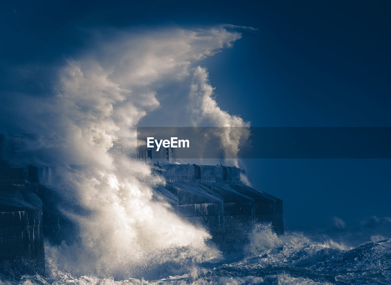 Waves hitting on shore against sky