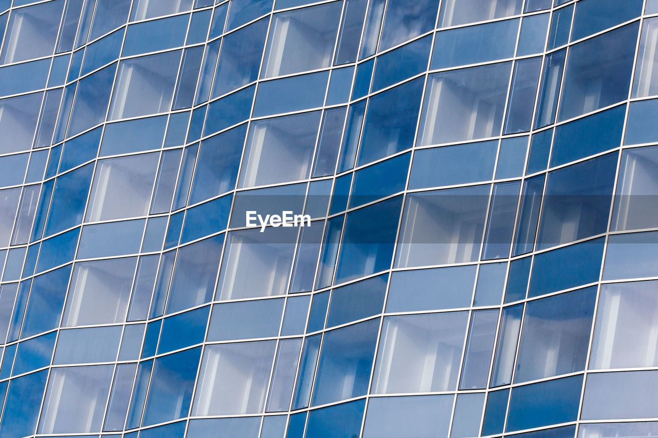 LOW ANGLE VIEW OF MODERN GLASS BUILDING IN CITY