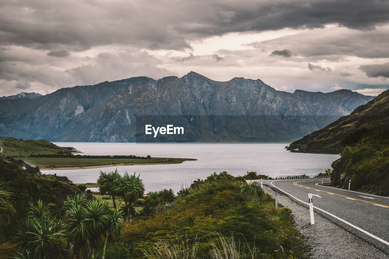 Scenic view of lake by mountains against cloudy sky