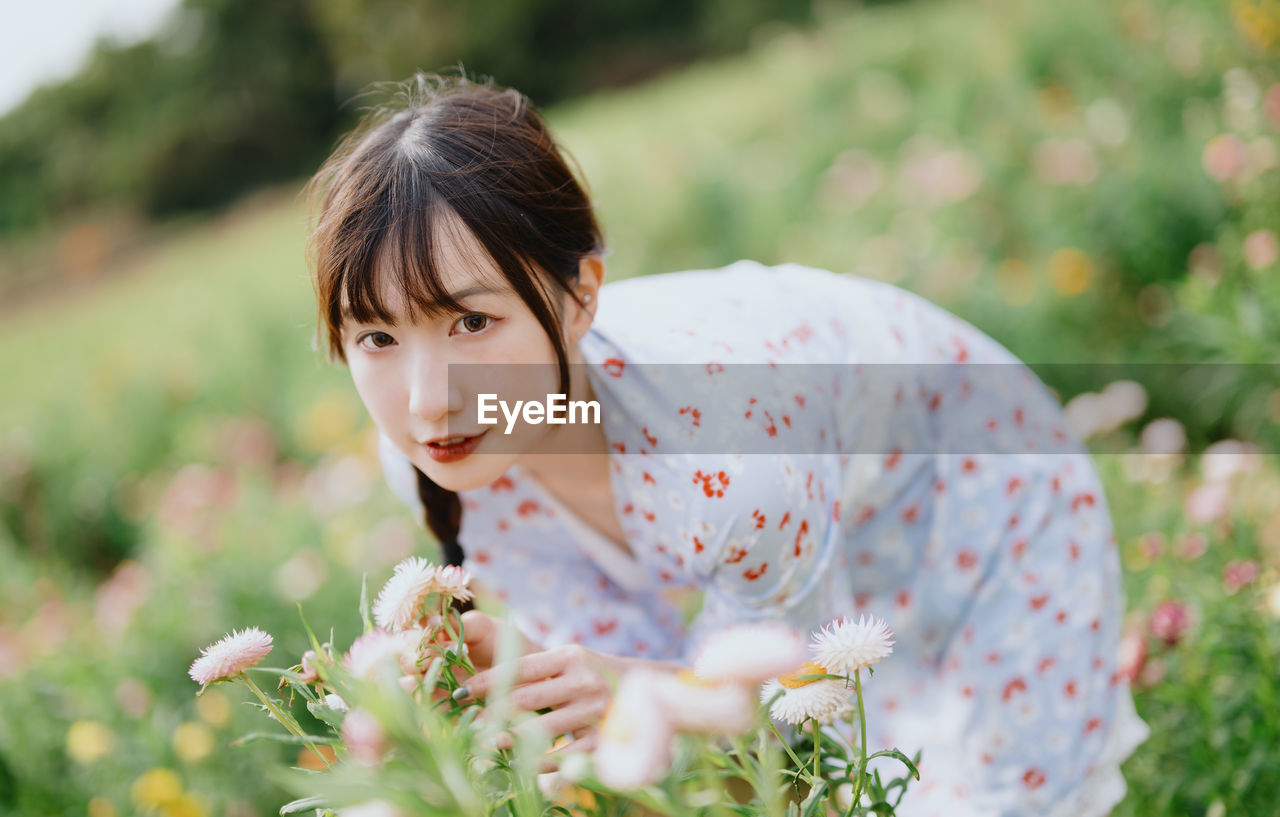 portrait of smiling young woman standing by plants