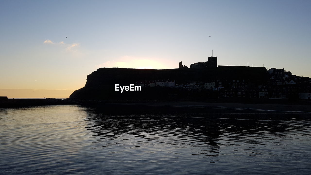 SILHOUETTE OF BUILDINGS AT SEA