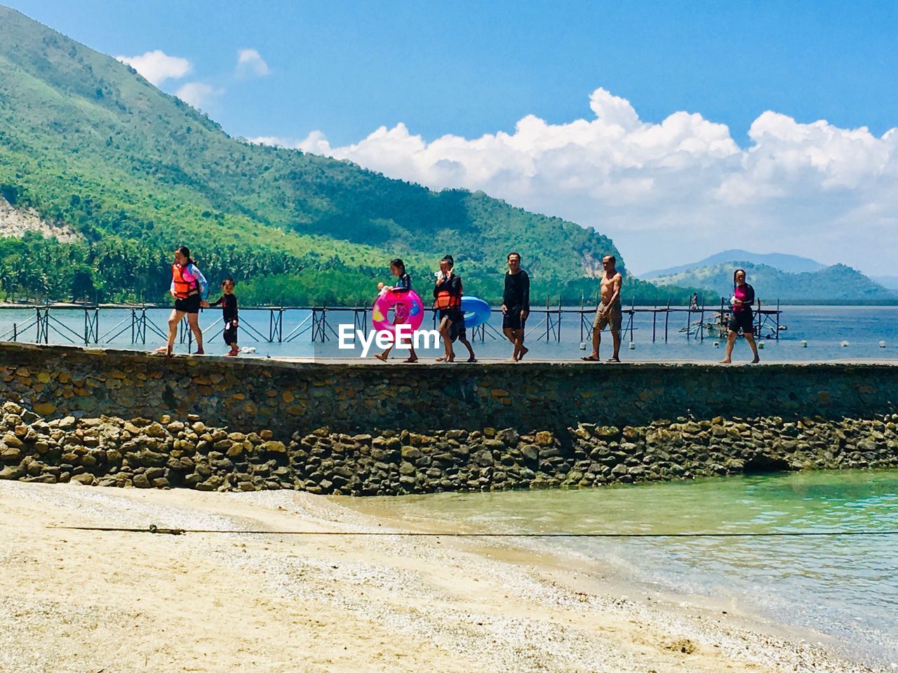 PEOPLE ON SHORE AGAINST MOUNTAINS