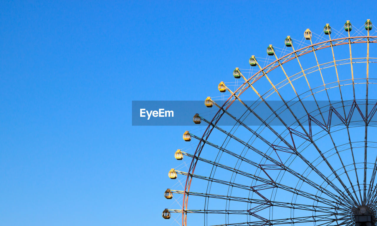 High section of cropped ferris wheel against clear blue sky