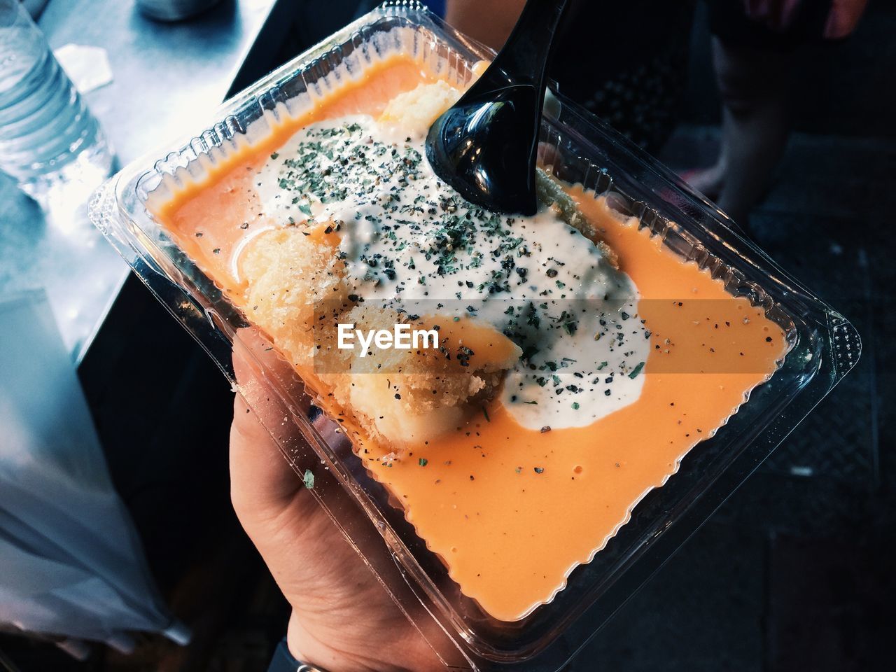 High angle view of hand holding curry in plastic plate
