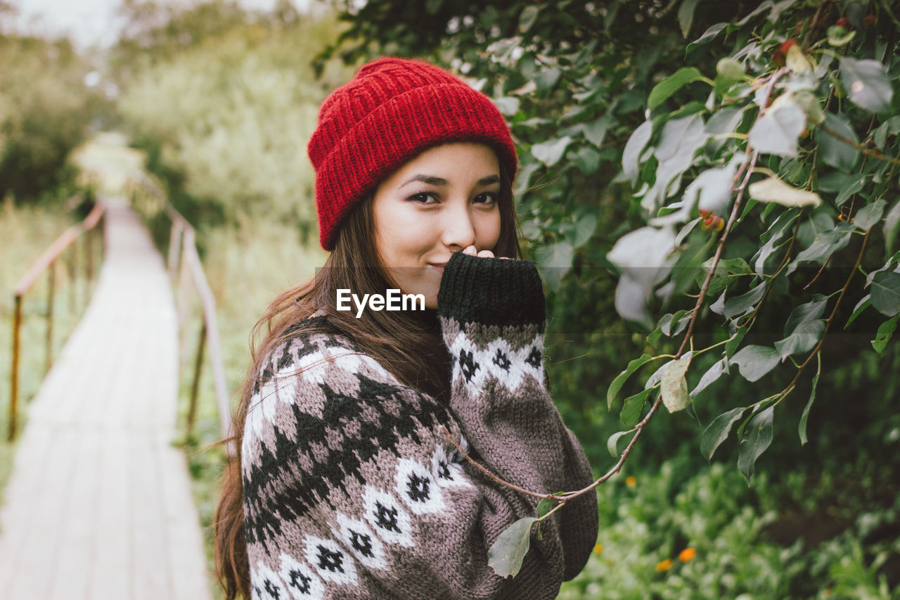 Portrait of smiling young woman standing on footpath