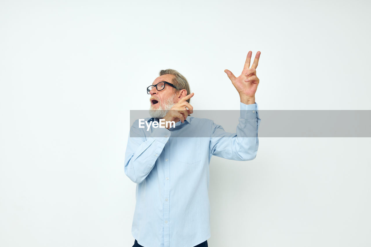 Senior man gesturing against white background