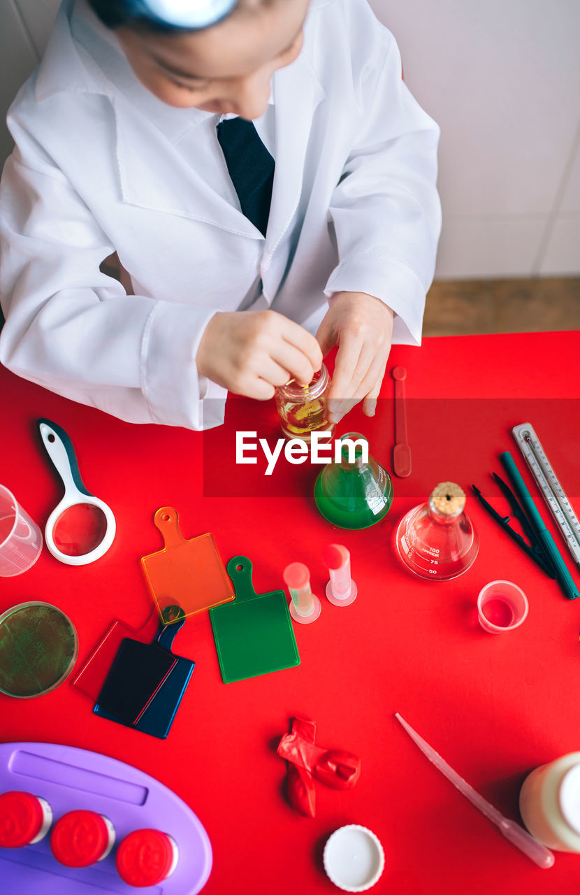 High angle view of boy wearing lab coat while mixing chemicals in classroom